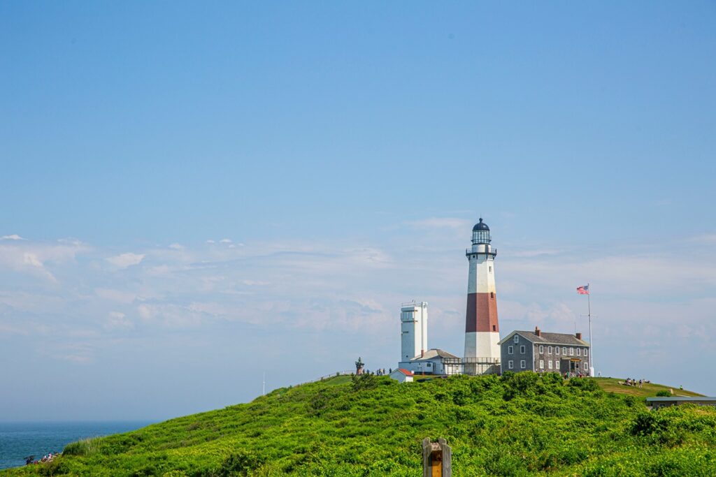 A red and white lighthouse on the lush hills of East Hampton