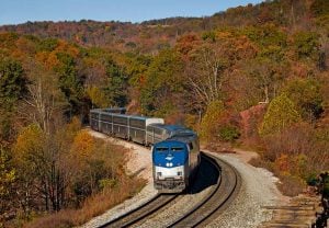 An Amtrak train weaves through fall foliage in New England.