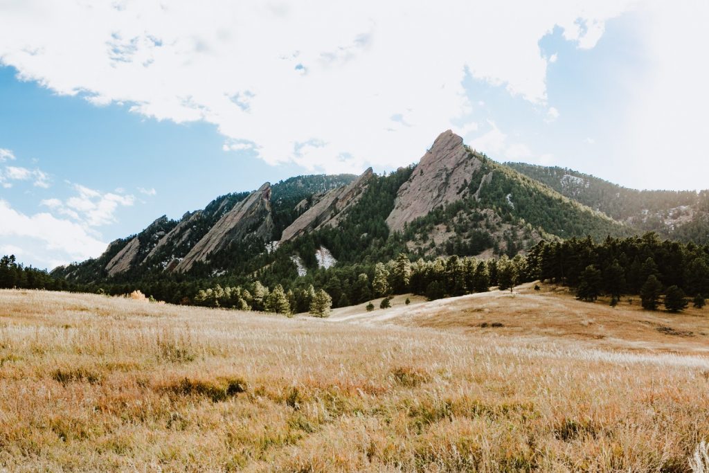 A grassy plain in front of a sharp mountain peak in Boulder
