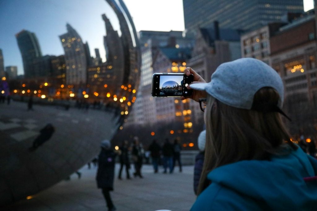A traveler snaps a photo of Chicago's Cloud Gate