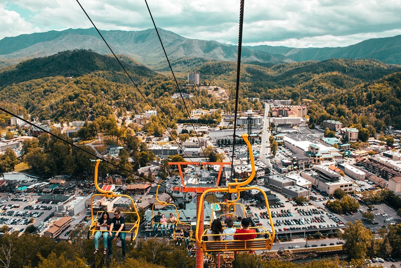 An aerial view of Pigeon Forge is the backdrop for a family on a ski lift up the mountain.