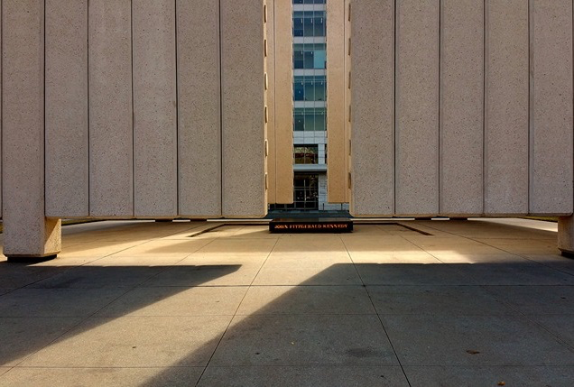 A close-in photo of the JFK Memorial in Texas, with two walls framing a black plaque