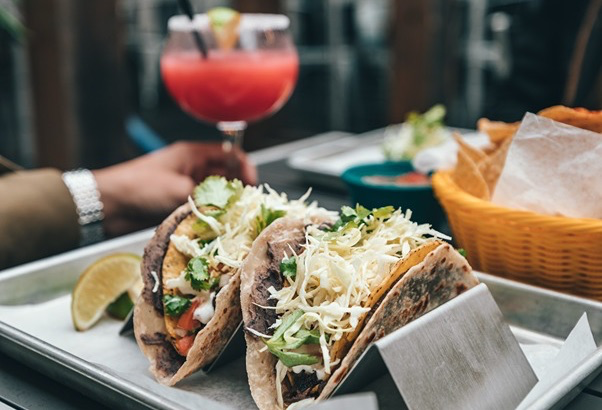 A Tex-Mex meal including tacos, chips, and a margarita