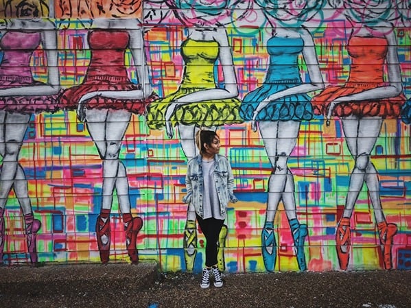 A woman poses in front of a colorful mural in Houston