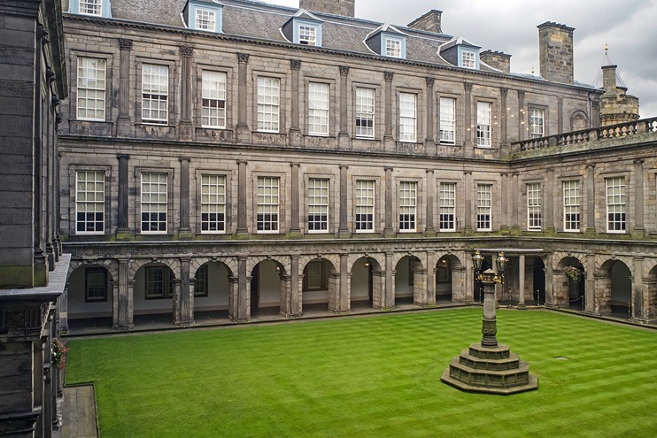 A grassy courtyard in the middle of a large palace, Holyroodhouse in Edinburgh, Scotland