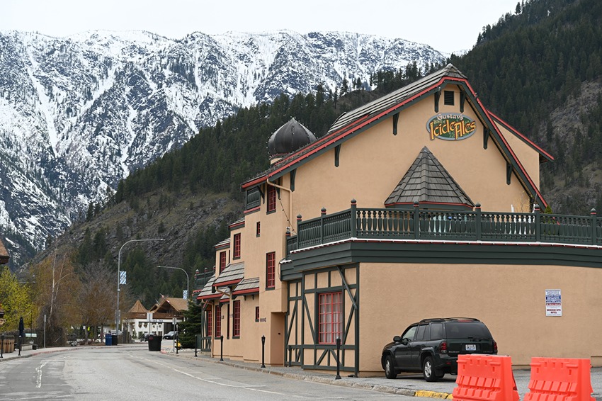 An icy road passes a Bavarian-style building before continuing into the snowy mountains