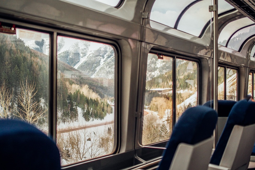 Train car interior looking out the window to snow and mountain landscapes