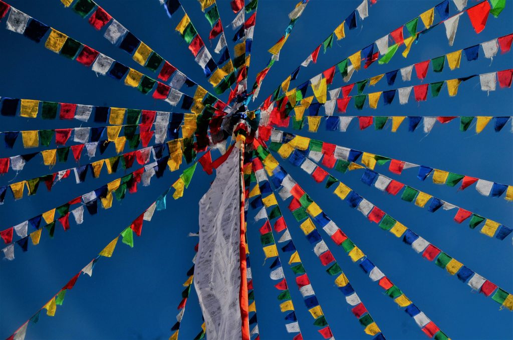 Tibetan prayer flags radiating outward against a blue sky